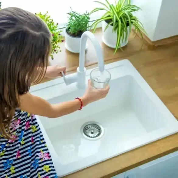 Fille qui rempli un verre d'eau