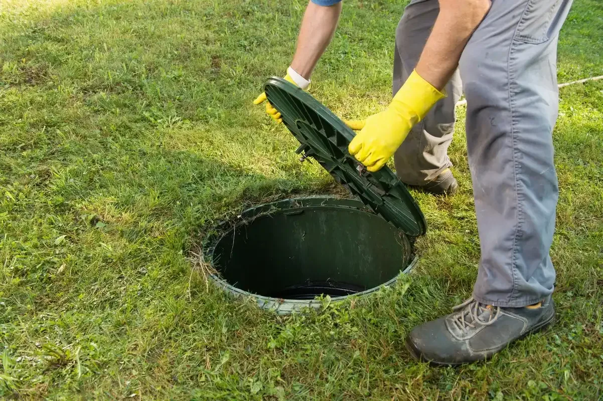 Plombier qui ouvre une fosse sceptique pour un curage de canalisation